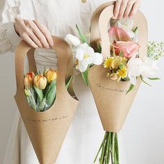 a woman holding two flower bouquets in their hands