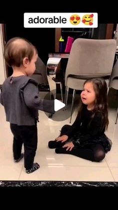 two young children sitting on the floor playing with each other in front of a chair