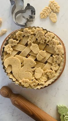 an uncooked pie sitting on top of a table next to cookie cutters