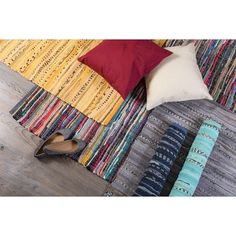 a pair of black shoes sitting on top of a rug next to a red pillow