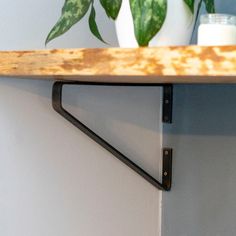 a potted plant sitting on top of a wooden shelf next to a white wall