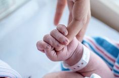 a close up of a baby's hand holding the finger of someones hand