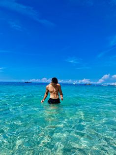 a man standing in the ocean with his back to the camera