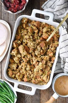 a casserole dish filled with stuffing next to green beans and cranberries