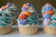 several cupcakes with different colored frosting and decorations on them are sitting on a white surface