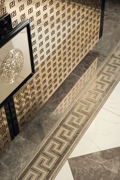 an art deco tile floor with gold and black designs on the wall next to it