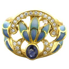 A sweet and stylish piece by Barcelona based designer Masriera. Known for their Art Nouveau style, this piece is no exception with the lovely bright yellow gold mixed with the blue sapphire and hand-painted enamel. The enamel is applied without a packing like a stained-glass window, an advanced technique called Pliqué-a-jour in French. The ring is also studded with round brilliant-cut diamonds which add sparkle and brilliance to the wonderful piece. Made in bright 18k yellow gold and ready to be Gold Enamel Jewelry, Enamel Rings, Sparkly Things, Art Nouveau Style, 18k Gold Ring, 18k Yellow Gold Ring, Gold Enamel