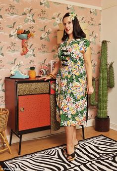 a woman standing in front of a wallpapered room with a zebra print rug