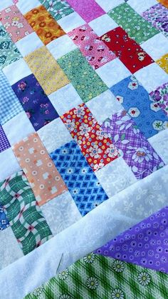 a colorful quilt is laying on top of a tablecloth that has many different colored squares