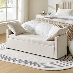 a white bed sitting on top of a hard wood floor next to a large window