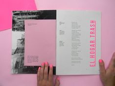 two hands are holding an open brochure on a pink surface