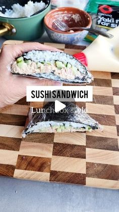 sushi sandwich being held up on a cutting board