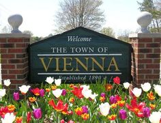 the welcome sign to the town of vienna is surrounded by colorful tulips and daffodils