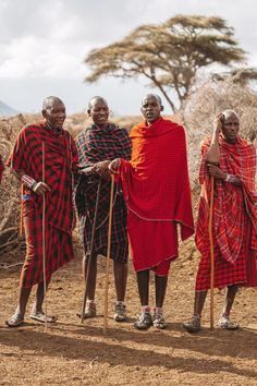 three men in red and black clothing standing next to each other with canes on their heads