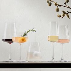 three wine glasses filled with different wines on a table next to an olive sprig