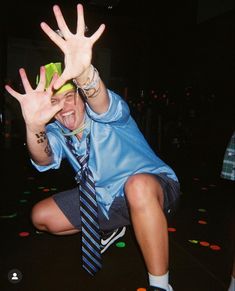 a man in a blue shirt and tie is holding his hands up