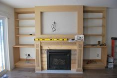 an empty living room with a fireplace and shelves