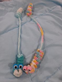 a necklace with two small stuffed animals attached to it's sides on a bed