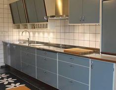 a kitchen with gray cabinets and white tile backsplashes on the walls, along with an area rug