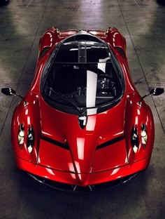 a red sports car is parked in a garage with its hood up and lights on