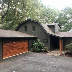 a house with two garages in front of it and lots of trees behind it