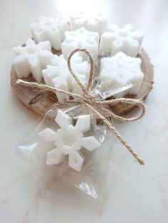 some white candles are wrapped in plastic and tied with twine on a wooden slice