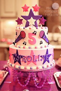 a pink and purple birthday cake with musical notes on the top is surrounded by other decorations