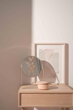 a wooden table with a mirror on top of it next to a plant in a vase