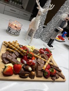 a wooden cutting board topped with lots of chocolate covered strawberries and other food items