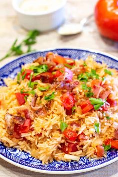 a close up of a plate of food with rice and meat on it, next to tomatoes