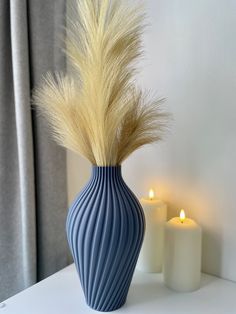 a blue vase sitting on top of a white table next to two candles and a window