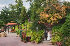 a bride and groom are standing on the steps in front of an outdoor garden area