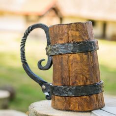 a close up of a wooden and metal mug on a table with grass in the background