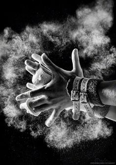 two hands reaching up into the air with clouds of dust behind them in black and white