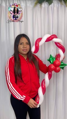 a woman is posing for a photo in front of a christmas balloon arch with candy canes