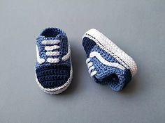 two crocheted baby shoes sitting on top of a gray floor next to each other