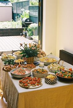 a table filled with lots of food on top of a white table covered in yellow cloths