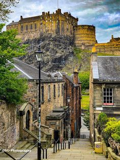 an old city street with stone buildings and a castle on the hill in the background