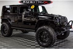 a black jeep is parked in a room with checkered flooring and a sign that says rubit trux