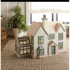 a toy house sitting on top of a rug next to a potted christmas tree