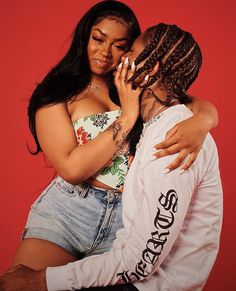 a man and woman embracing each other in front of a red background