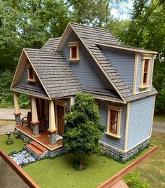 a doll house is shown on top of a wooden table in front of some trees