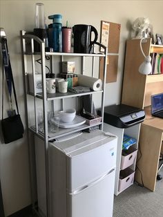 a refrigerator freezer sitting inside of a kitchen next to a shelf filled with cups