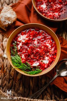 two bowls filled with cranberry sauce on top of a woven table cloth next to spoons