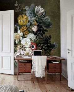 a desk with a laptop on top of it in front of a flower wall mural