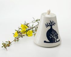 a white bell with a blue design on it next to yellow flowers