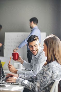 three people sitting at a table with laptops and coffee mugs in their hands