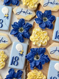 blue and yellow decorated cookies with flowers on them for a birthday or anniversary party decoration