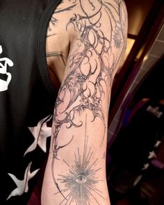 a man's arm with tattoos on it and an eye in the middle, surrounded by stars