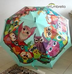 an umbrella with owls painted on it is sitting on the floor next to a rug